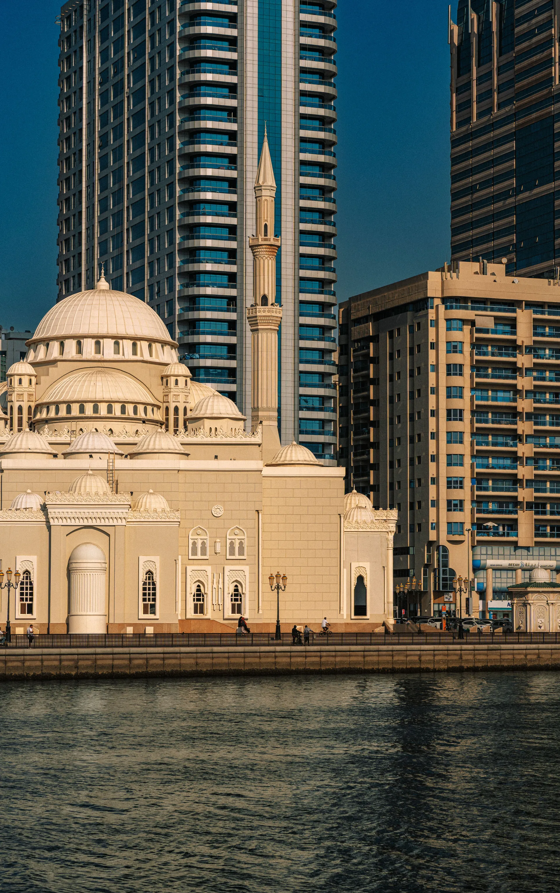 Al Noor Mosque beside Sharjah’s waterfront with towers behind it