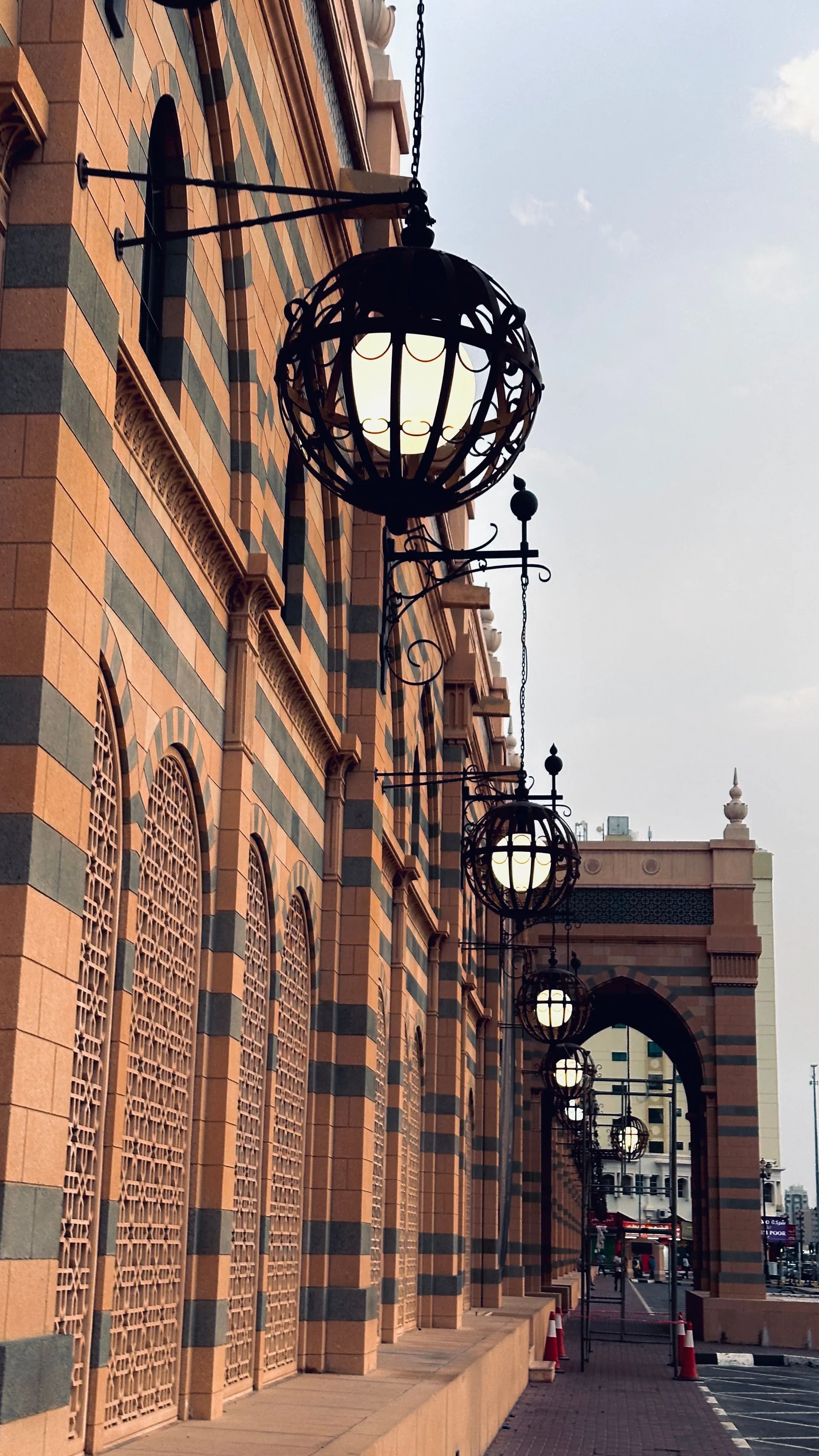 Hanging lanterns beside an ornate striped mosque facade