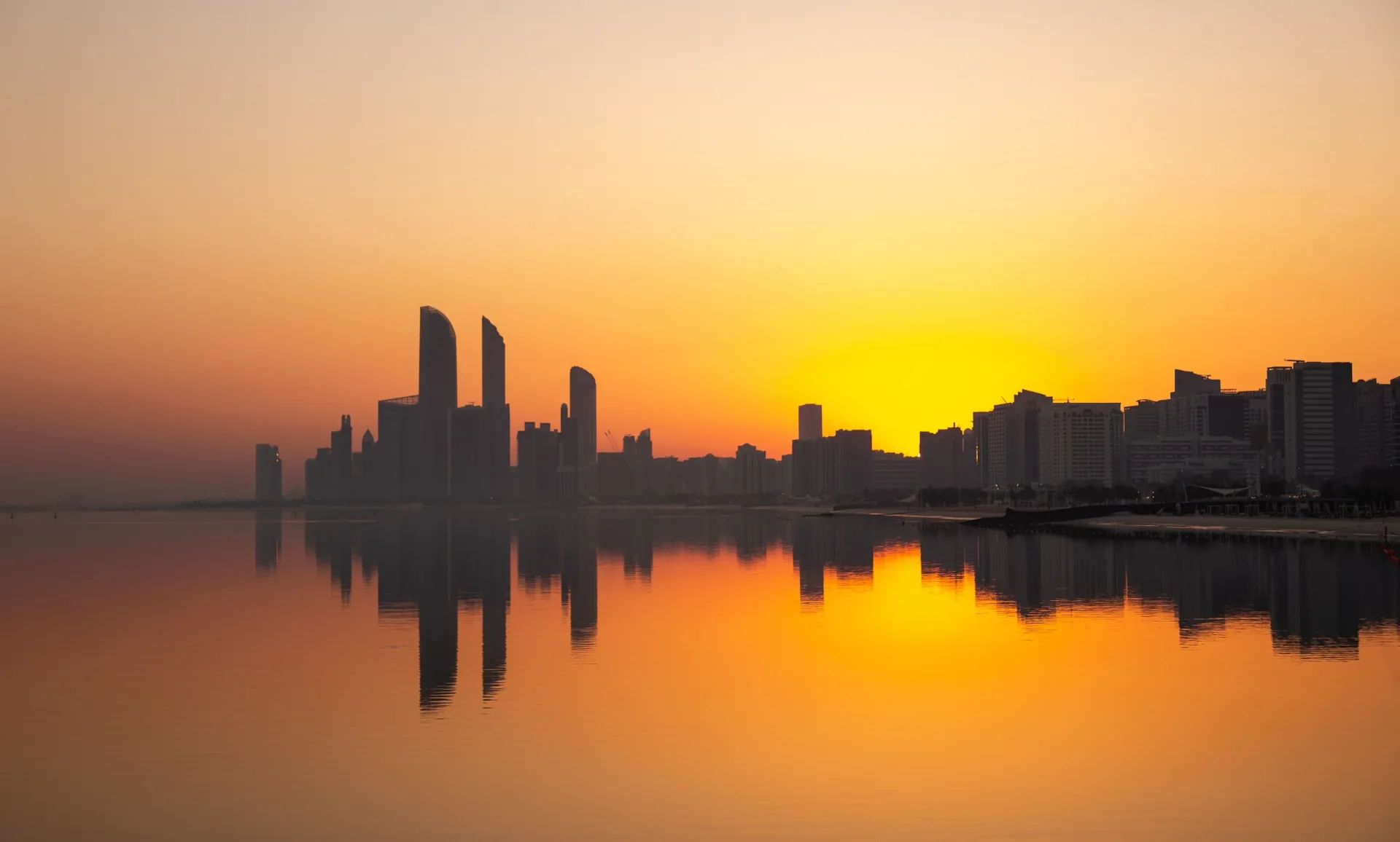 A waterfront skyline reflected in still water at sunset